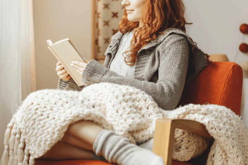 woman curled up with a book and a blanket