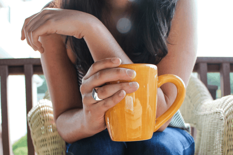 woman's hand grasping cup of coffee
